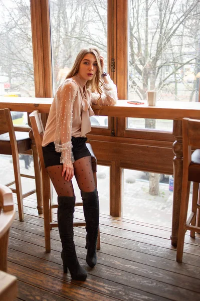 Una joven y bonita mujer en la cafetería. Grunge. Chica en un café en una blusa beige — Foto de Stock