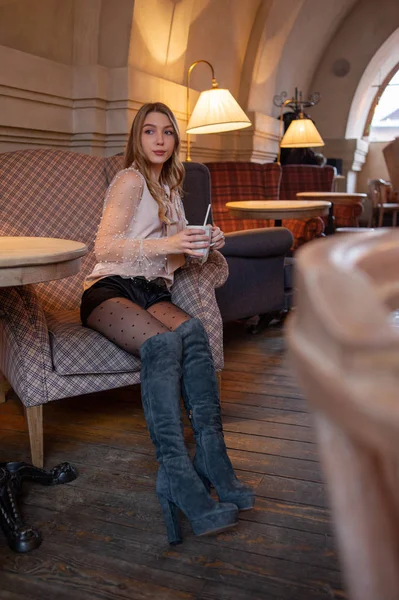 Una joven y bonita mujer en la cafetería. Grunge. Chica en un café con una blusa beige. Una chica bebe café en un café. Latte, Cappuccino — Foto de Stock