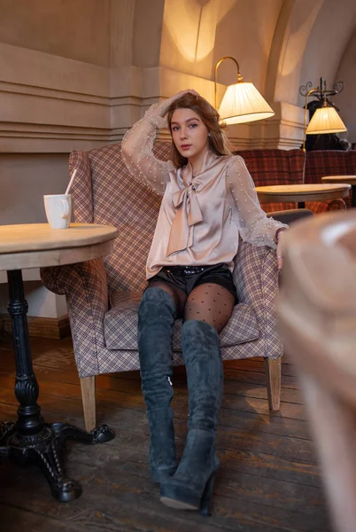 Una joven y bonita mujer en la cafetería. Grunge. Chica en un café con una blusa beige. Una chica bebe café en un café. Latte, Cappuccino — Foto de Stock