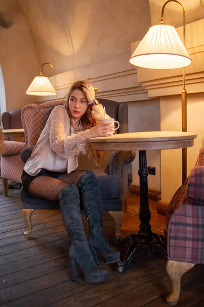 Una joven y bonita mujer en la cafetería. Grunge. Chica en un café con una blusa beige. Una chica bebe café en un café. Latte, Cappuccino — Foto de Stock