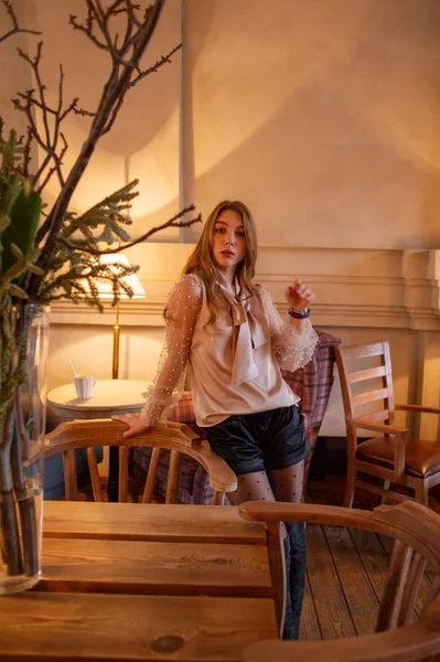 Jeune jolie femme au café. Grunge. Fille dans un café dans un chemisier beige — Photo