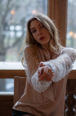 Kafedeki genç ve güzel kadın. Grunge. Kafede bej bluzlu bir kız.