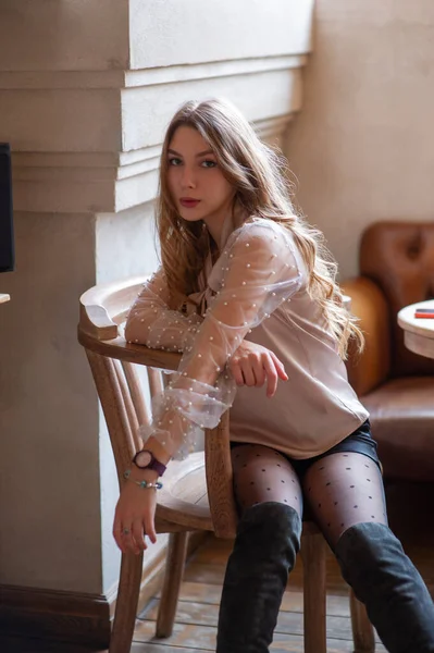 Una joven y bonita mujer en la cafetería. Grunge. Chica en un café en una blusa beige — Foto de Stock