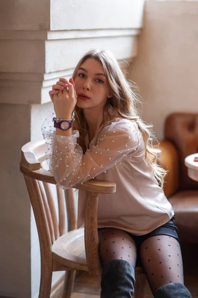 Una joven y bonita mujer en la cafetería. Grunge. Chica en un café en una blusa beige — Foto de Stock