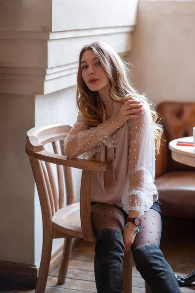 Una joven y bonita mujer en la cafetería. Grunge. Chica en un café en una blusa beige — Foto de Stock