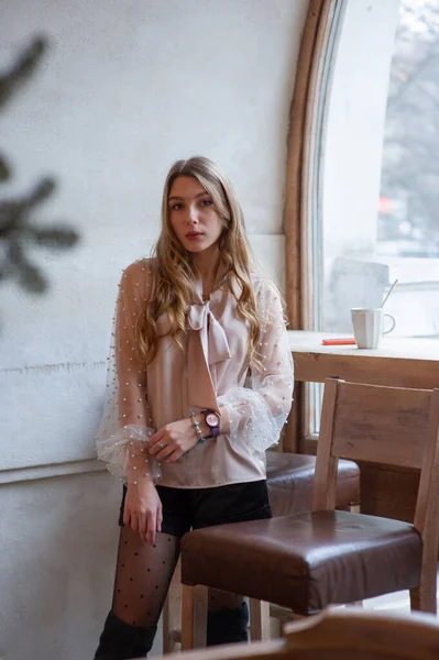 Una joven y bonita mujer en la cafetería. Grunge. Chica en un café en una blusa beige — Foto de Stock