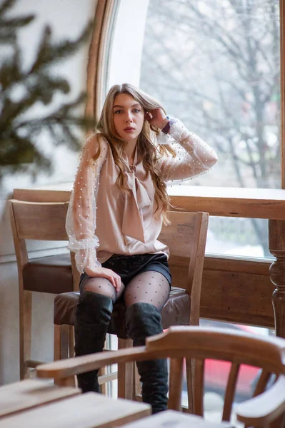 Una joven y bonita mujer en la cafetería. Grunge. Chica en un café en una blusa beige — Foto de Stock