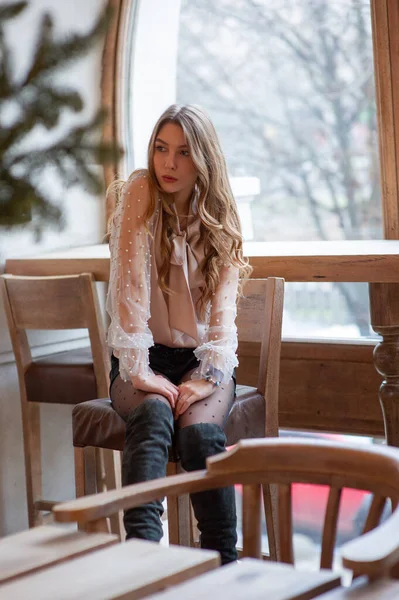 Una joven y bonita mujer en la cafetería. Grunge. Chica en un café en una blusa beige — Foto de Stock