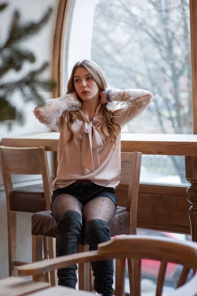 Una joven y bonita mujer en la cafetería. Grunge. Chica en un café en una blusa beige — Foto de Stock