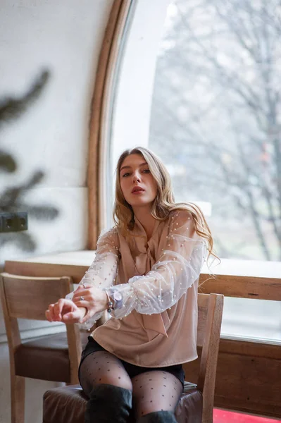 Jonge mooie vrouw in café. Grunge. Meisje in een cafe in een beige blouse — Stockfoto