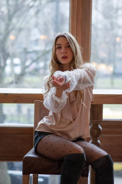 Una joven y bonita mujer en la cafetería. Grunge. Chica en un café en una blusa beige — Foto de Stock