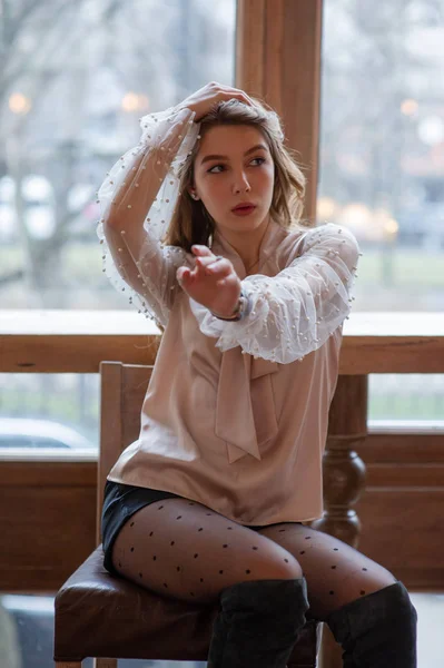 Una joven y bonita mujer en la cafetería. Grunge. Chica en un café en una blusa beige — Foto de Stock