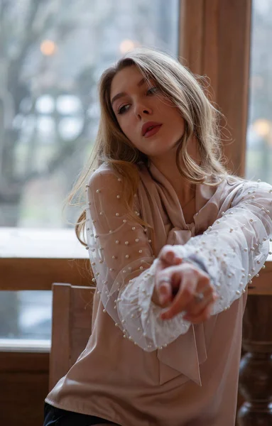 Una joven y bonita mujer en la cafetería. Grunge. Chica en un café en una blusa beige — Foto de Stock