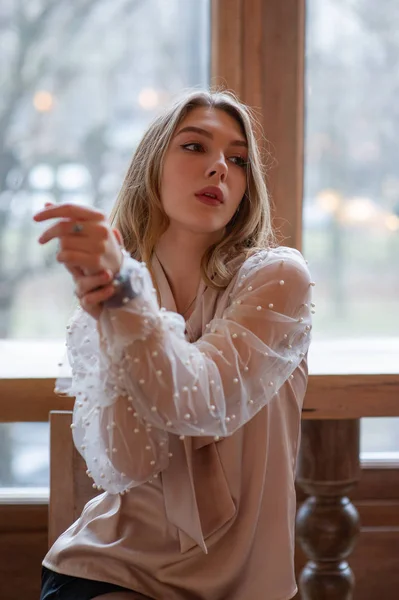 Una joven y bonita mujer en la cafetería. Grunge. Chica en un café en una blusa beige — Foto de Stock