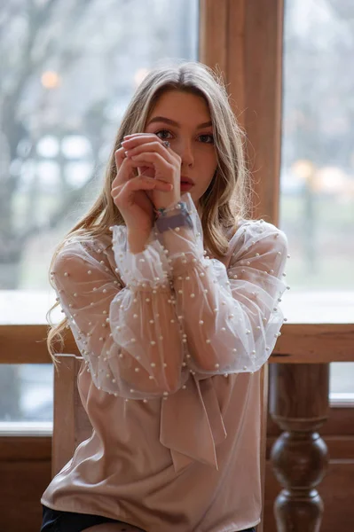 Jonge mooie vrouw in café. Grunge. Meisje in een cafe in een beige blouse — Stockfoto