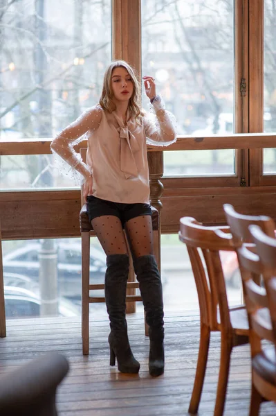 Una joven y bonita mujer en la cafetería. Grunge. Chica en un café en una blusa beige — Foto de Stock