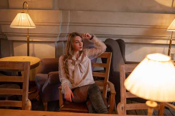 Ung vacker kvinna i caféet. Grunge. Flicka på ett kafé i en beige blus — Stockfoto