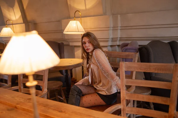 Jeune jolie femme au café. Grunge. Fille dans un café dans un chemisier beige — Photo