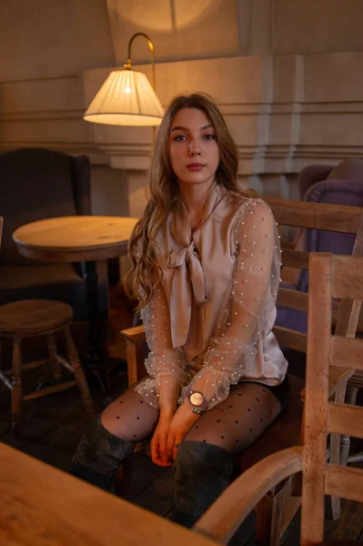 Jonge mooie vrouw in café. Grunge. Meisje in een cafe in een beige blouse — Stockfoto