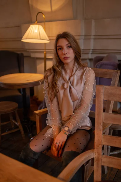 Una joven y bonita mujer en la cafetería. Grunge. Chica en un café en una blusa beige —  Fotos de Stock