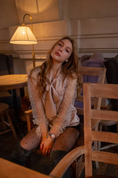 Una joven y bonita mujer en la cafetería. Grunge. Chica en un café en una blusa beige — Foto de Stock