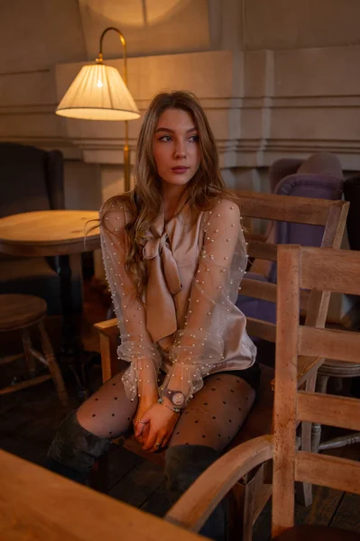 咖啡店里的年轻漂亮的女人。 闷闷不乐 穿着米色衬衫在咖啡店里的女孩 — 图库照片