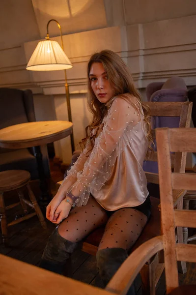 Jonge mooie vrouw in café. Grunge. Meisje in een cafe in een beige blouse — Stockfoto