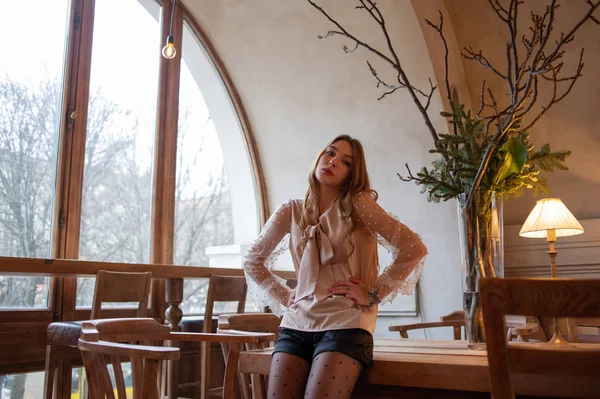 Jeune jolie femme au café. Grunge. Fille dans un café dans un chemisier beige — Photo