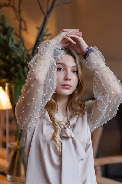 Una joven y bonita mujer en la cafetería. Grunge. Chica en un café en una blusa beige — Foto de Stock