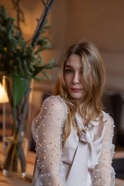 Una joven y bonita mujer en la cafetería. Grunge. Chica en un café en una blusa beige — Foto de Stock