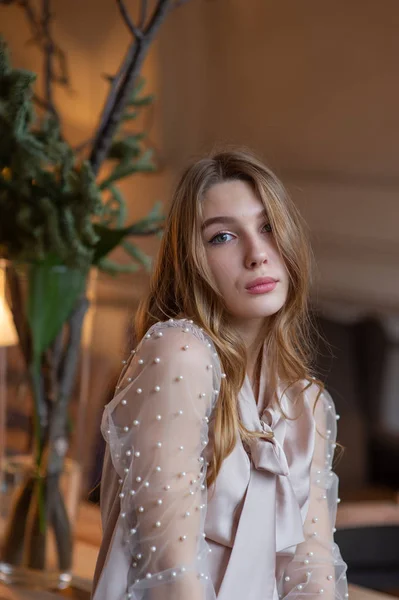 Una joven y bonita mujer en la cafetería. Grunge. Chica en un café en una blusa beige — Foto de Stock