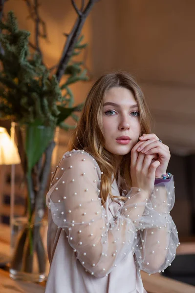 Jonge mooie vrouw in café. Grunge. Meisje in een cafe in een beige blouse — Stockfoto