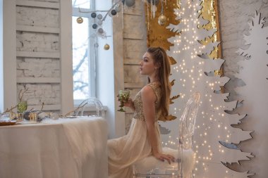 Parlak bir gece elbisesi giyen kız. Noel arifesi. Kürk ağacında rahat bir tatil Işıklar ve altın dekorla