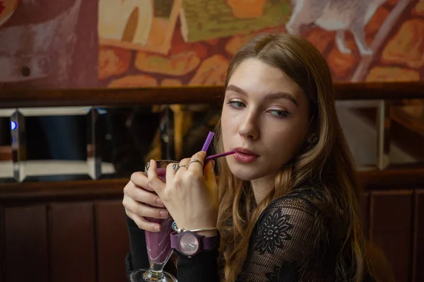 Chica en un vestido negro con un cóctel en un café — Foto de Stock