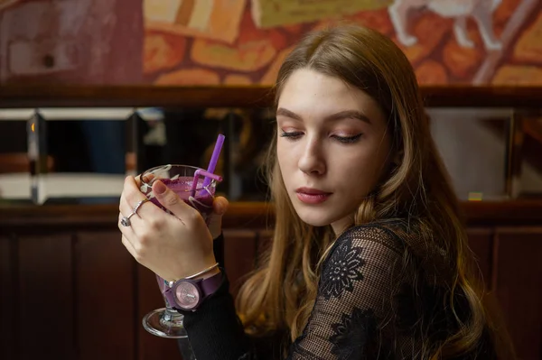 Chica en un vestido negro con un cóctel en un café — Foto de Stock