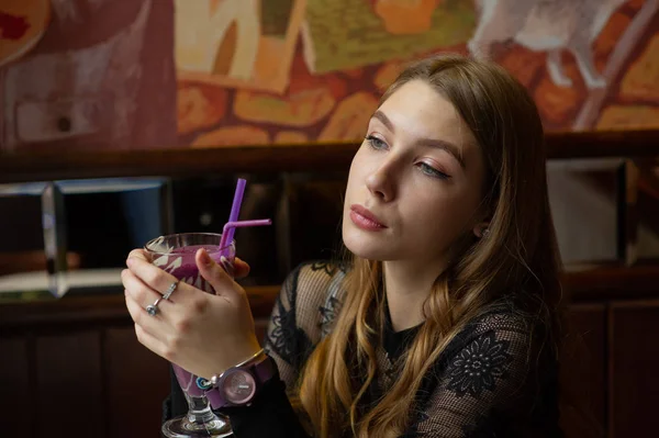 Flicka i svart klänning med en cocktail på ett café — Stockfoto