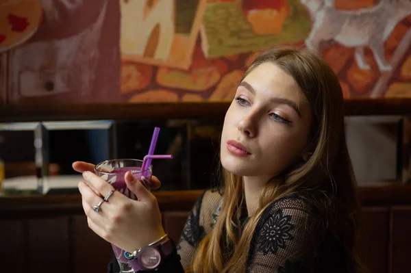 Chica en un vestido negro con un cóctel en un café — Foto de Stock