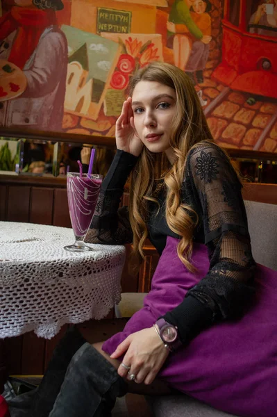 穿着黑色连衣裙在咖啡店里喝鸡尾酒的女孩 — 图库照片