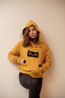 Karanlık çekici gözlerle kameraya bakarak karanlık düz uzun saçlı gevşek kazak giyen esmer oldukça çekici genç kadın. Gri studio duvara poz güzel kız.