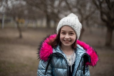 Sahibinin kollarında küçük bir chihuahua yatıyor. Okul çocuğu, kışlık giysiler içinde sokakta. 9 yaşında bir kız..