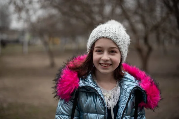 Een kleine chihuahua ligt in de armen van zijn eigenaar. Schoolkind in winterkleren op straat. Meisje 9 jaar oud. — Stockfoto