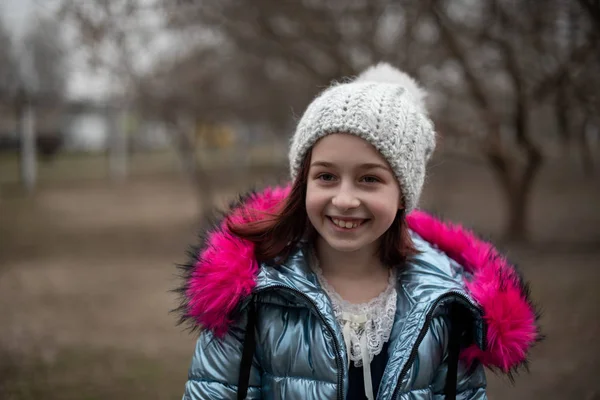 Een kleine chihuahua ligt in de armen van zijn eigenaar. Schoolkind in winterkleren op straat. Meisje 9 jaar oud. — Stockfoto