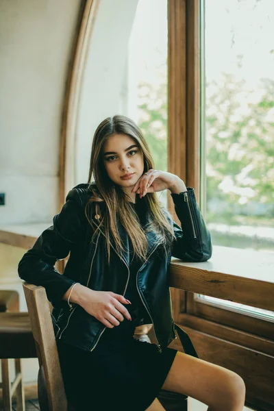 Menina morena elegante bonita vestindo um vestido preto é relaxante em um café de rua. Publicidade, moda. Foto matizada — Fotografia de Stock