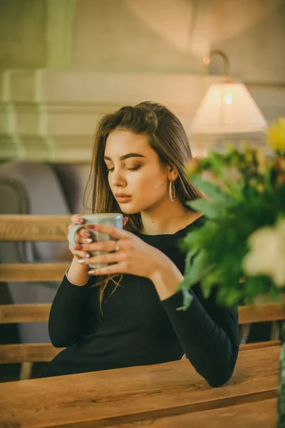 Schöne elegante brünette Mädchen in einem schwarzen Kleid entspannt in einem Straßencafé. Werbung, Mode. getöntes Foto — Stockfoto