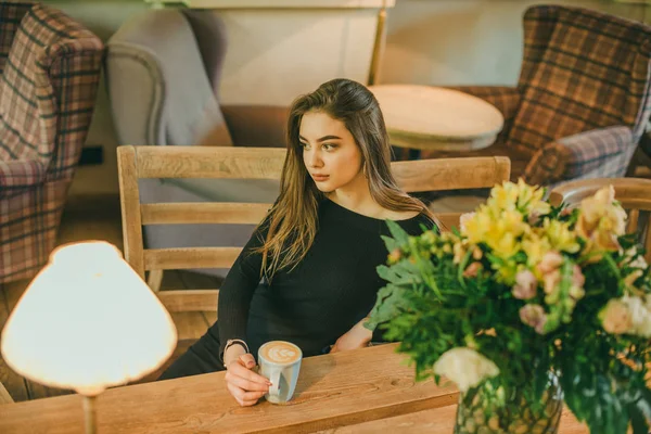 Красива елегантна брюнетка дівчина в чорній сукні розслабляється у вуличному кафе. Реклама, мода. Тонована фотографія — стокове фото