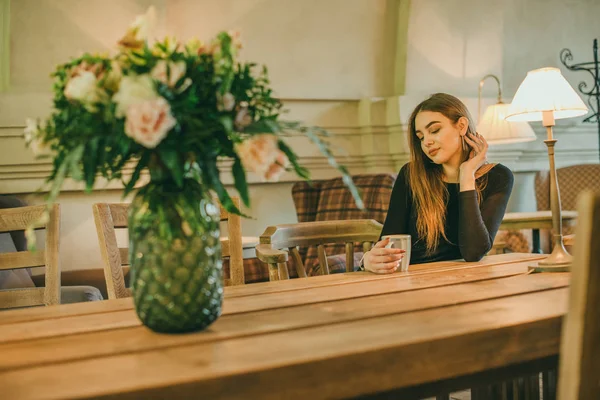 Schöne elegante brünette Mädchen in einem schwarzen Kleid entspannt in einem Straßencafé. Werbung, Mode. getöntes Foto — Stockfoto