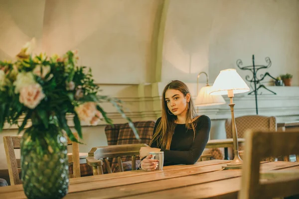 Schöne elegante brünette Mädchen in einem schwarzen Kleid entspannt in einem Straßencafé. Werbung, Mode. getöntes Foto — Stockfoto