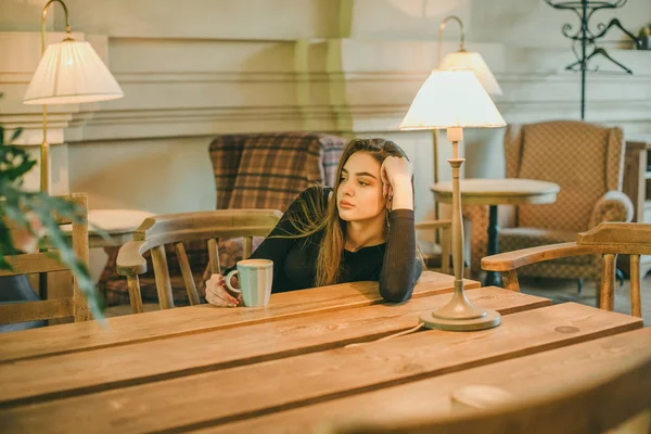 Schöne elegante brünette Mädchen in einem schwarzen Kleid entspannt in einem Straßencafé. Werbung, Mode. getöntes Foto — Stockfoto