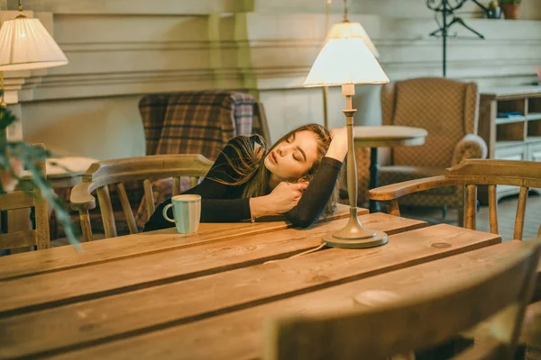 Schöne elegante brünette Mädchen in einem schwarzen Kleid entspannt in einem Straßencafé. Werbung, Mode. getöntes Foto — Stockfoto