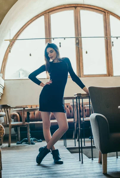 Krásná elegantní brunetka dívka v černých šatech je relaxační v pouliční kavárně. Reklama, móda. Tónovaná fotografie — Stock fotografie